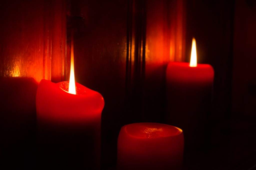 3 red burning candles lighting the darkness.