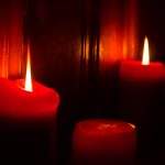 3 red burning candles lighting the darkness.